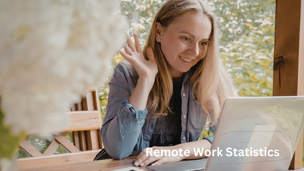 Woman smiling and waving during a video call while working on a laptop at home, illustrating remote work statistics and work-from-home trends.